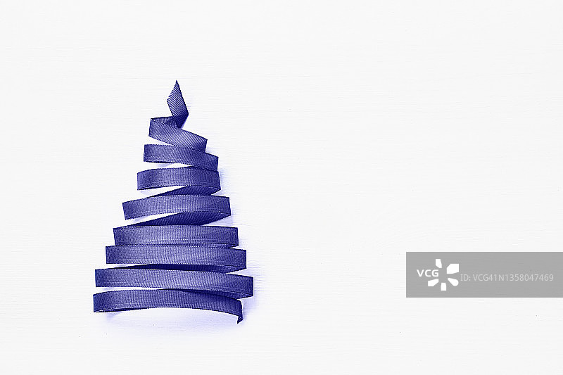白色背景上用淡紫色丝带做成的圣诞树。非常Peri 2022颜色。本空间图片素材
