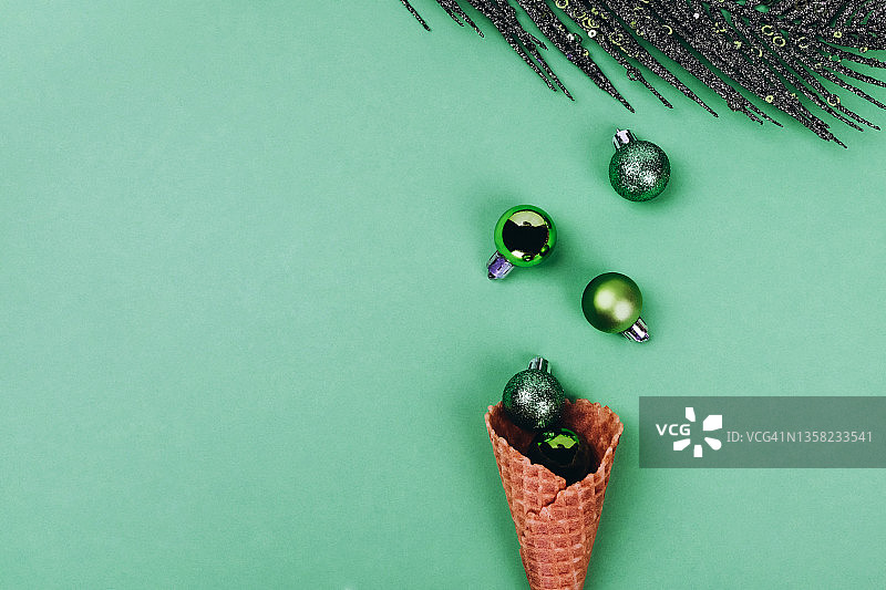 华夫蛋筒和绿色不同发光圣诞玩具上面有闪光的叶子。图片素材