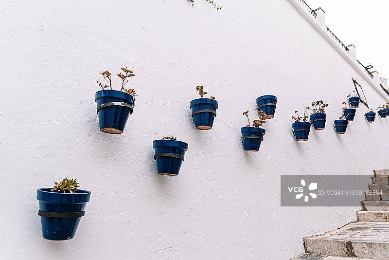 在马拉加的Mijas村，蓝色的花盆挂在白色的墙上。图片素材