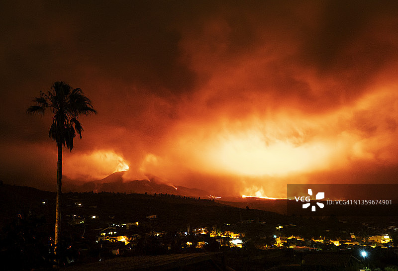 火山在夜间喷发。Cumbre Vieja火山在Tajuya镇的房子旁边，浓烟滚滚，熔岩滚滚。图片素材