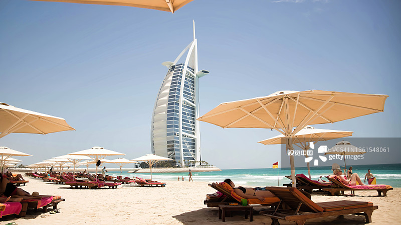 图为，在阿联酋迪拜的Burj al Arab酒店前的朱美拉海滩上，人们正在享受阳光灿烂的一天图片素材