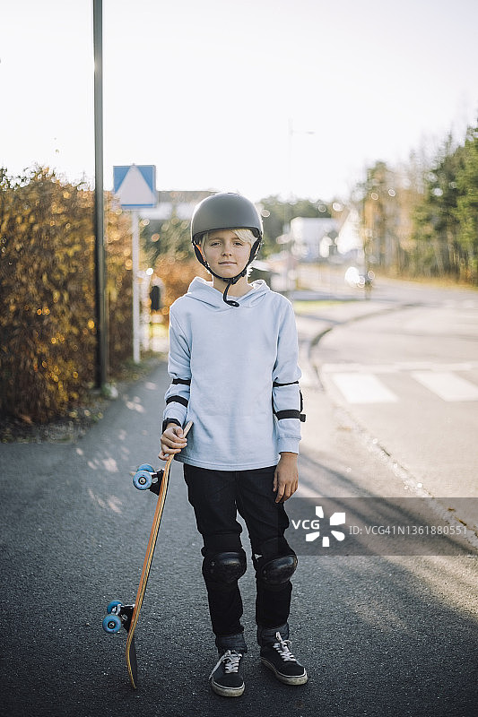 白色滑板男孩站在路上的肖像图片素材