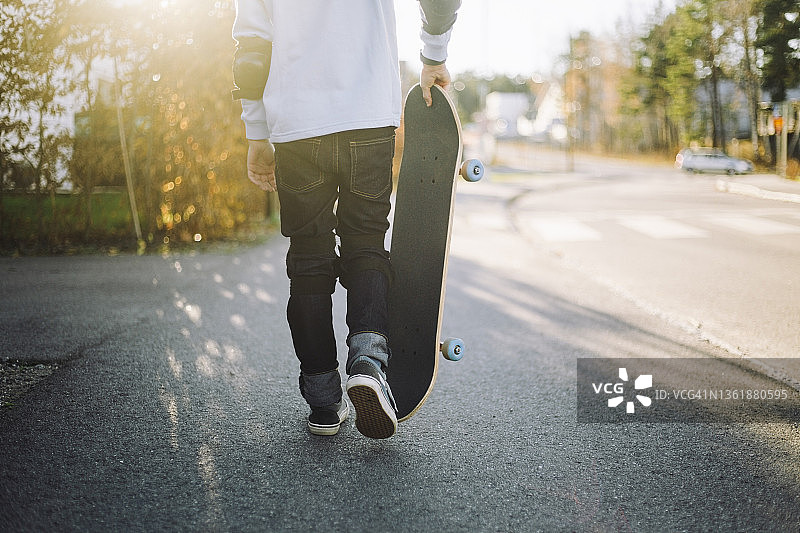 低节的男孩踩着滑板走在路上图片素材