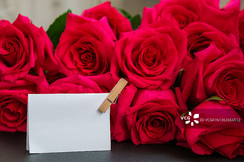 粉红色的玫瑰和白色的空纸笔记的文本复制空间。假期的模拟。情人节，母亲节。邀请贺卡图片素材