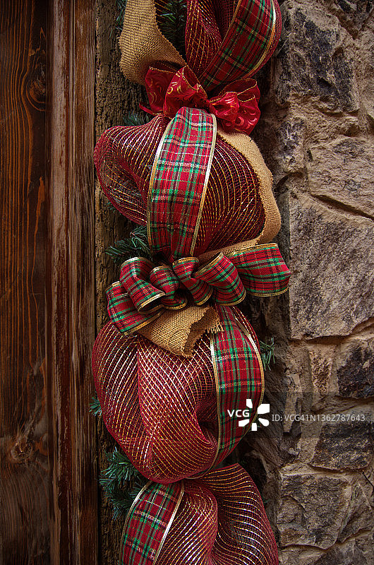 门口是红色、金色和绿色的格子彩带和天然的粗麻绳圣诞花环和人造针叶树花环图片素材