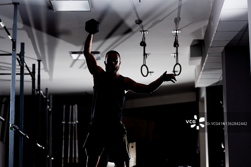 一个肌肉发达的运动员举起非常重的重量的轮廓。男子在室内锻炼图片素材