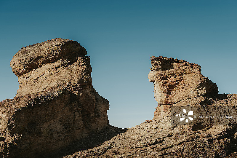 在沙漠地区，两根引人注目的石柱矗立在蓝天下图片素材
