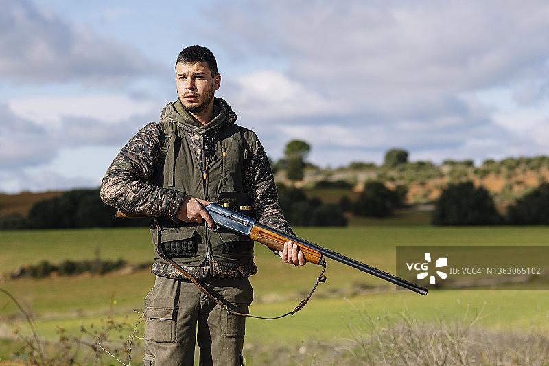 男性猎人的肖像，握着枪和寻找新的猎物，而狩猎在野外。图片素材
