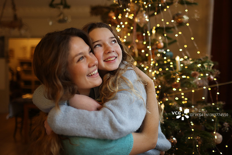 两姐妹在圣诞树前拥抱图片素材
