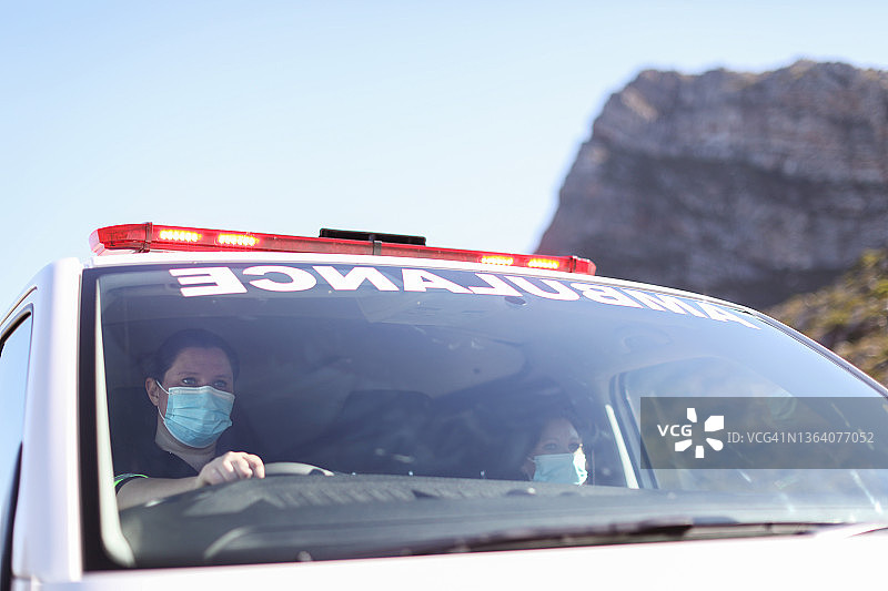两名女护理人员驾驶一辆救护车前往紧急地点。图片素材