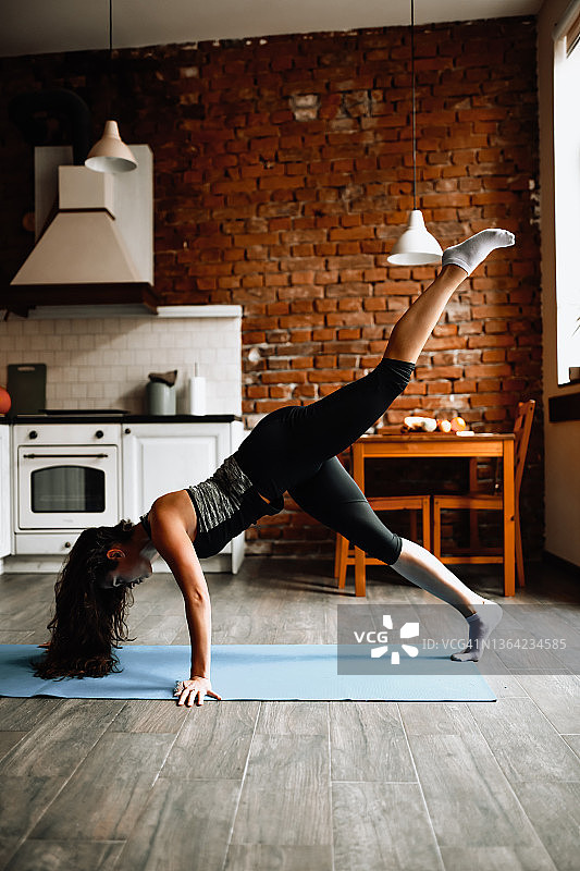 女运动员伸展腿与平板运动在厨房图片素材