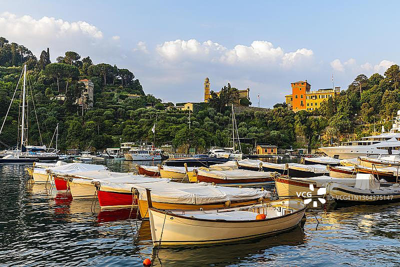 豪华游艇停泊在意大利利古里亚的波托菲诺港，圣乔治教堂后面图片素材