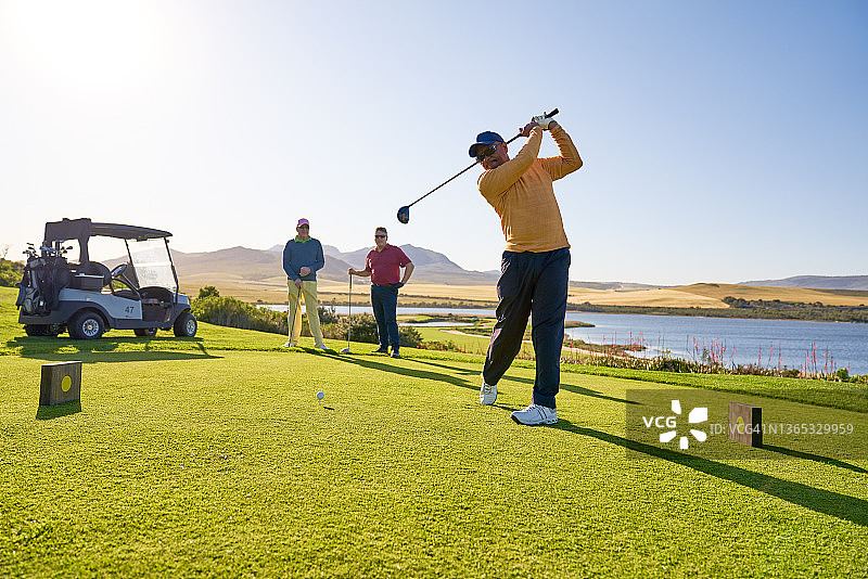 男性高尔夫球手在阳光明媚的高尔夫球座开球图片素材