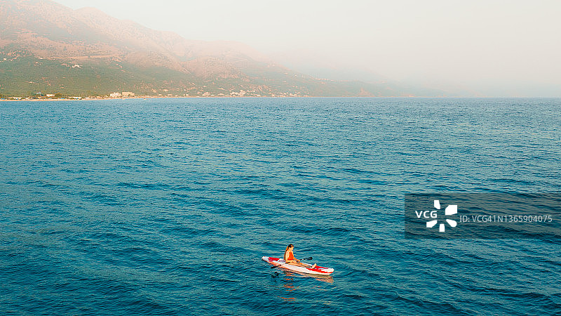 鸟瞰图，阿尔巴尼亚女子在碧绿的大海上划皮艇图片素材