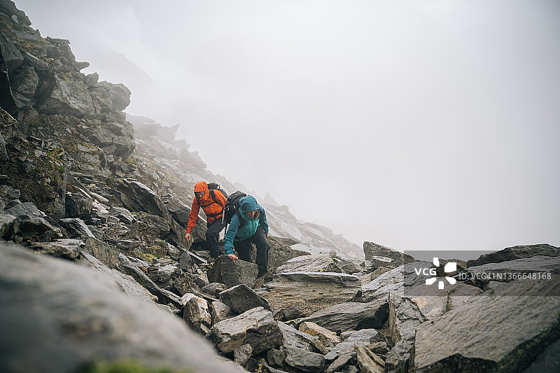 登山运动员爬上多岩石的山脊图片素材