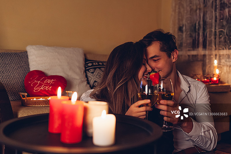 情人节，一对相爱的情侣在家里，手握酒杯，喝着酒，吃着浪漫的晚餐图片素材