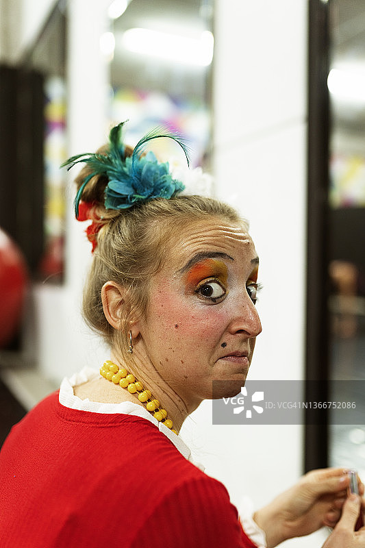 马戏团女小丑表演者在表演和训练前对着镜子化妆。图片素材