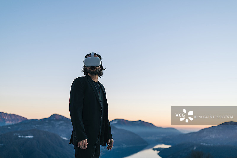 商人戴着VR眼镜在山脊上图片素材