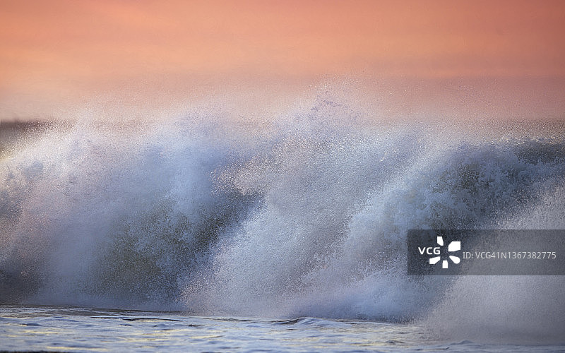 惊人的海浪撞击粉红色的天空海景在开普五月，新泽西州图片素材