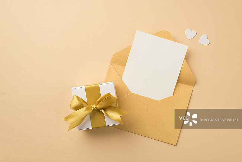 俯视图照片开放的蜡笔黄色信封与纸白纸白心和白色礼盒与金丝带蝴蝶结孤立的米色背景与空白的空间图片素材