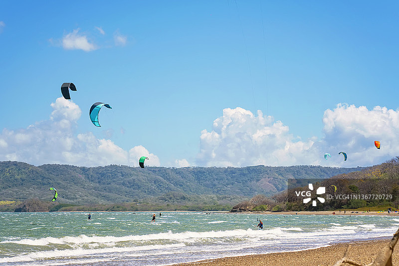 在哥斯达黎加，人们在海上对着山脉和天空玩风筝滑板图片素材