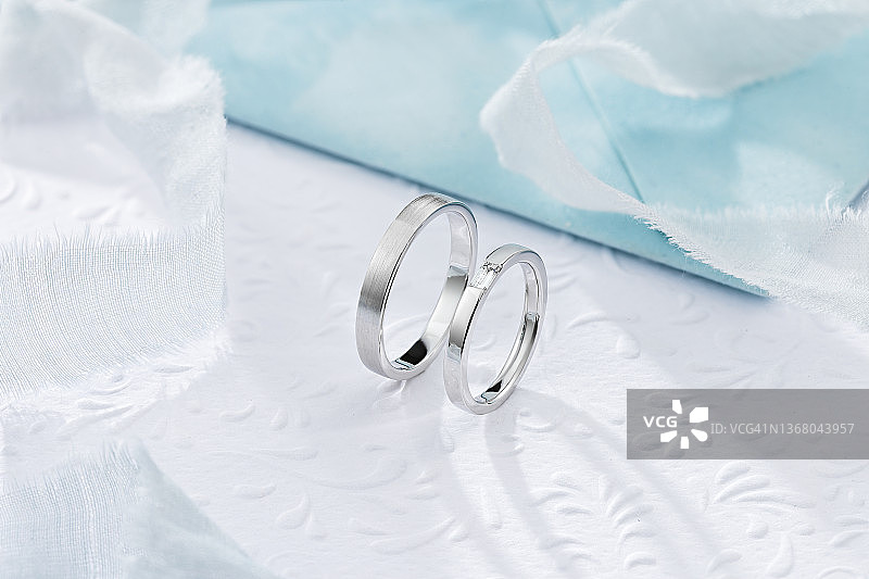 一对时尚的银质结婚戒指，蓝色和白色的背景图片素材