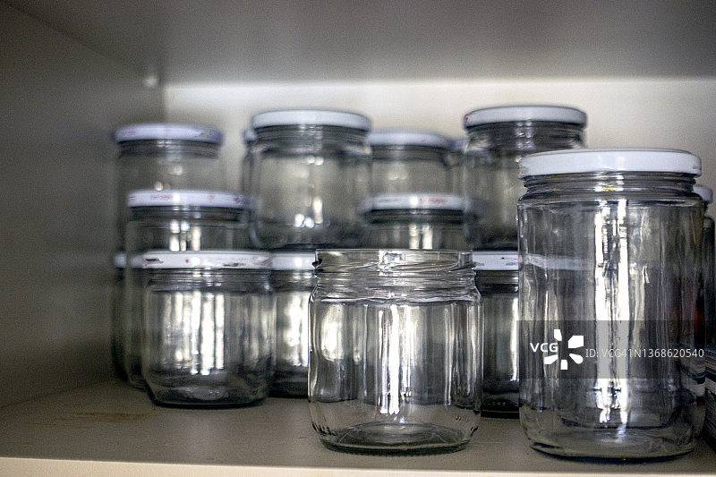碗柜架子上的空罐头瓶。玻璃罐图片素材