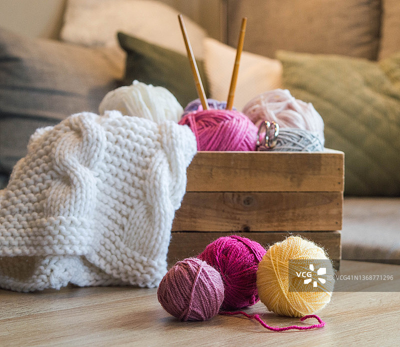 木盒里的彩色羊毛球，竹编针和一条白色的针织围巾图片素材