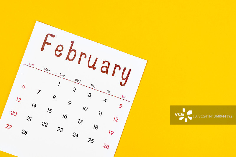 二月是组织者计划和提醒的月份，用黄色的纸做背景。商业计划预约会议概念图片素材