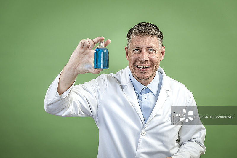 穿着白大褂的科学家，手里拿着一个装着蓝色液体的小烧瓶图片素材