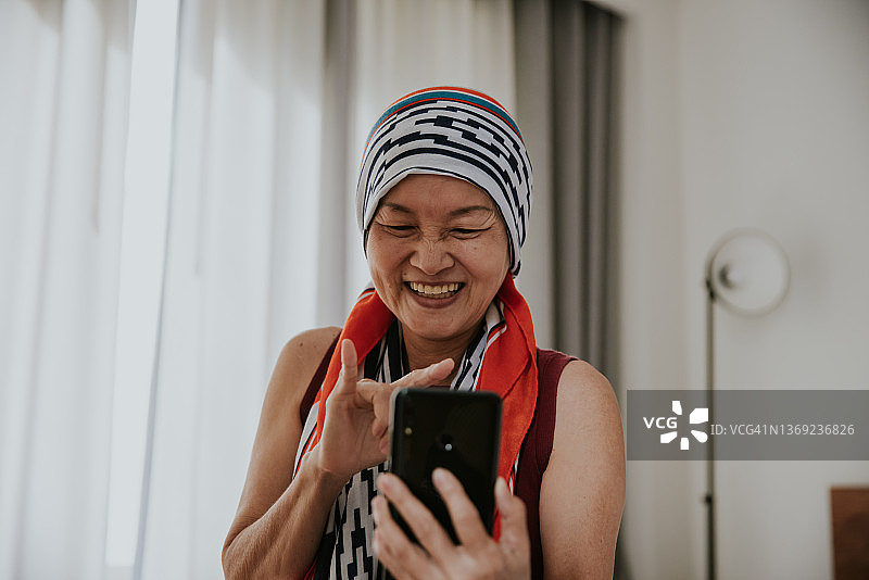 身患癌症的老年女性用智能手机与朋友视频聊天。图片素材