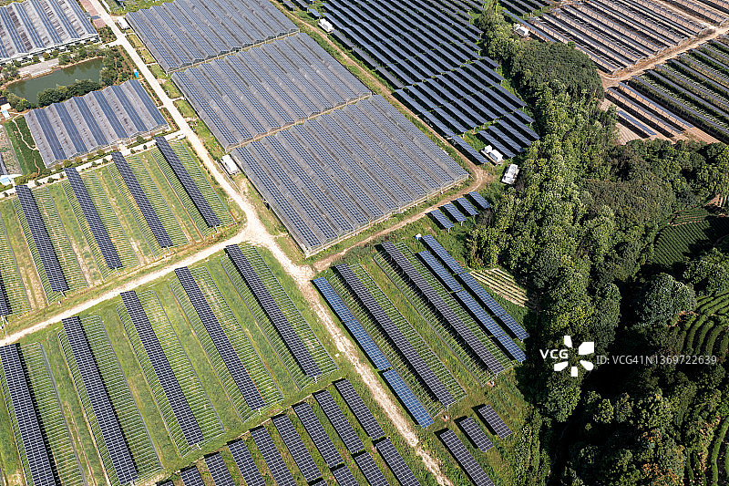 俯瞰郁郁葱葱的山谷，一排排整齐地排列着太阳能电池板图片素材