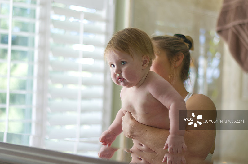 镜子前抱着宝宝的年轻妈妈图片素材