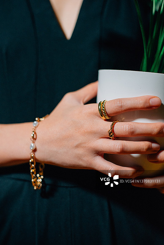 拿着花盆的女人手上戴着金戒指和手镯图片素材