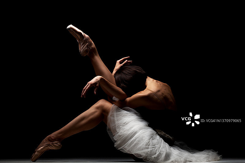 穿着芭蕾舞裙的芭蕾舞女演员在地板上摆姿势图片素材