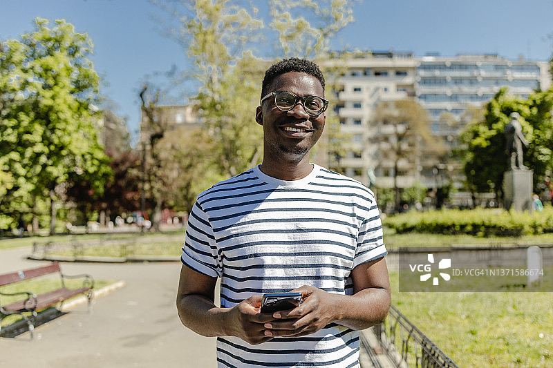 一个非裔美国年轻人在公园里用手机图片素材