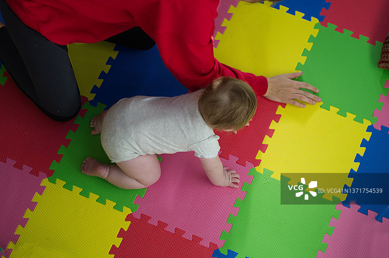 宝宝和妈妈一起在彩色垫子上爬行图片素材