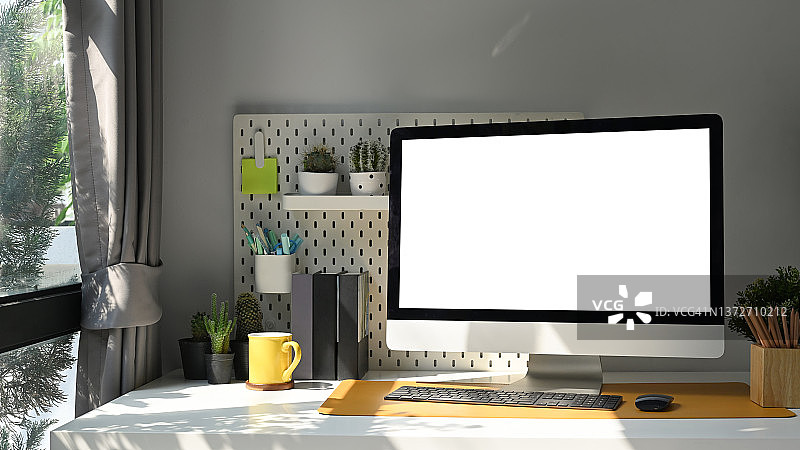 模拟电脑电脑空白显示器，室内植物和用品在白色的桌子在客厅。图片素材