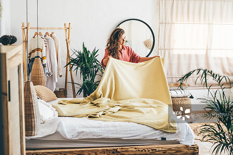 女人做着她的早晨例行公事，在家整理枕头和床铺。图片素材