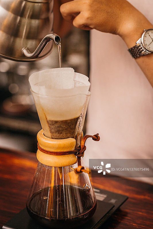 年轻的亚裔男咖啡师，穿着白衬衫，用化学咖啡机煮咖啡图片素材