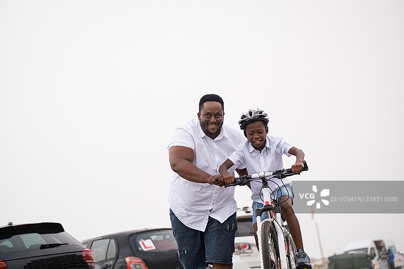 父亲在帮儿子骑自行车图片素材