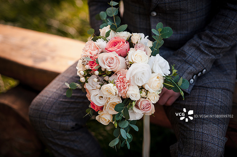 婚礼花束在新郎手中。美丽的新娘花束在一个男人的手中图片素材