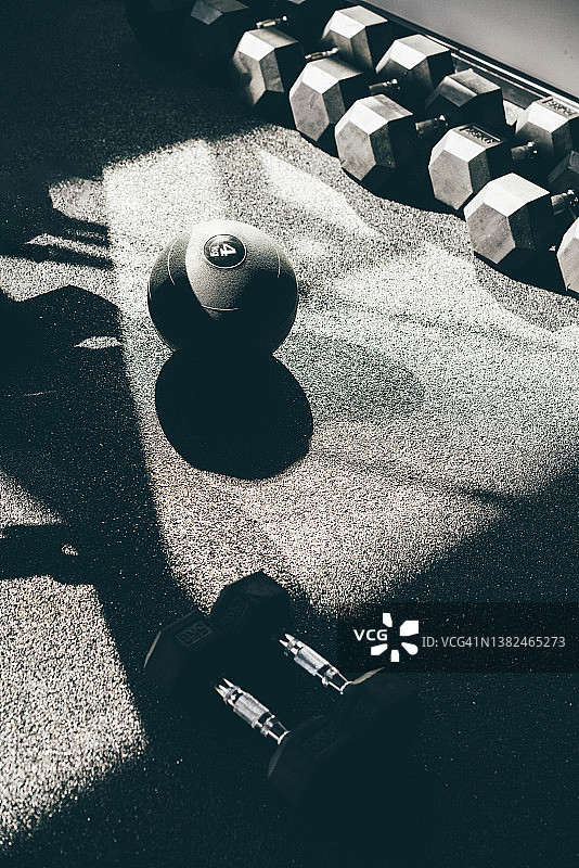 健身器材。体育馆地板上的实心球和一排排哑铃。图片素材
