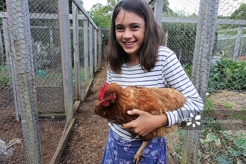 一个年轻的澳大利亚女孩在农场里抱着一只鸡图片素材