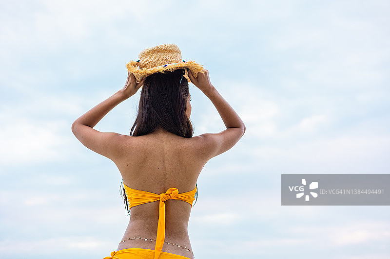 夏天，年轻女子头戴帽子坐在沙滩上图片素材