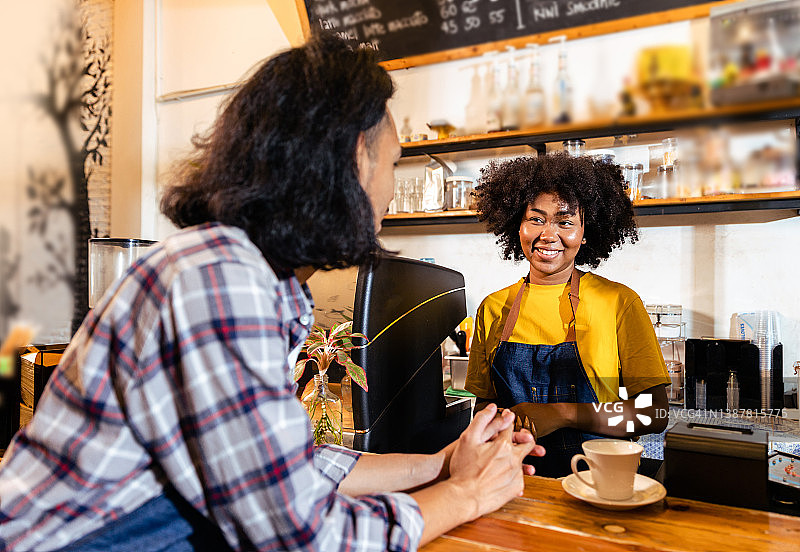 微笑的夫妇站在柜台上一起经营咖啡馆的肖像。快乐的服务生和服务员在咖啡馆摆姿势。中小企业的概念。图片素材