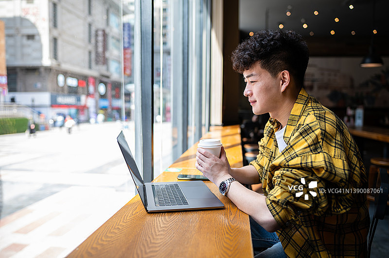 亚洲帅哥在咖啡厅用笔记本电脑图片素材
