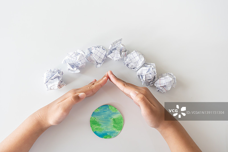 重复使用纸张保护世界。减少纸张的使用量将节省更多的树木。孩子的手保护世界。图片素材