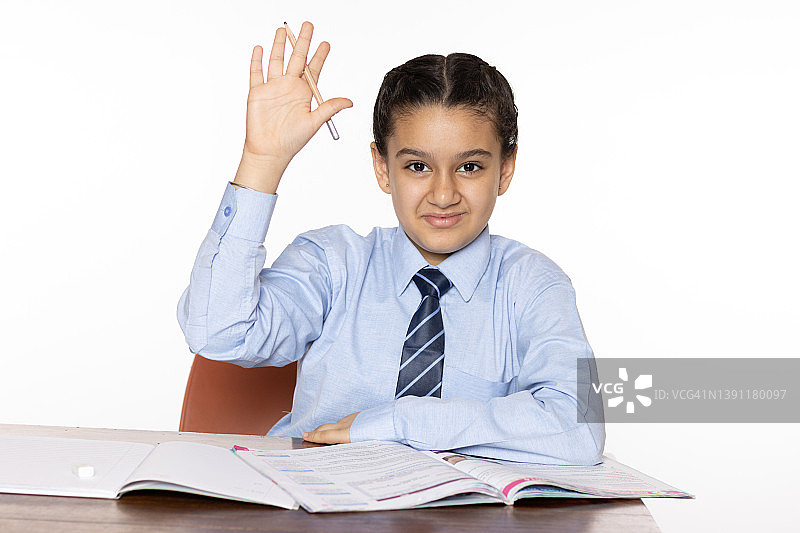 小学的小女孩坐在教室里举手回答一个孤立在白人背景下的问题图片素材