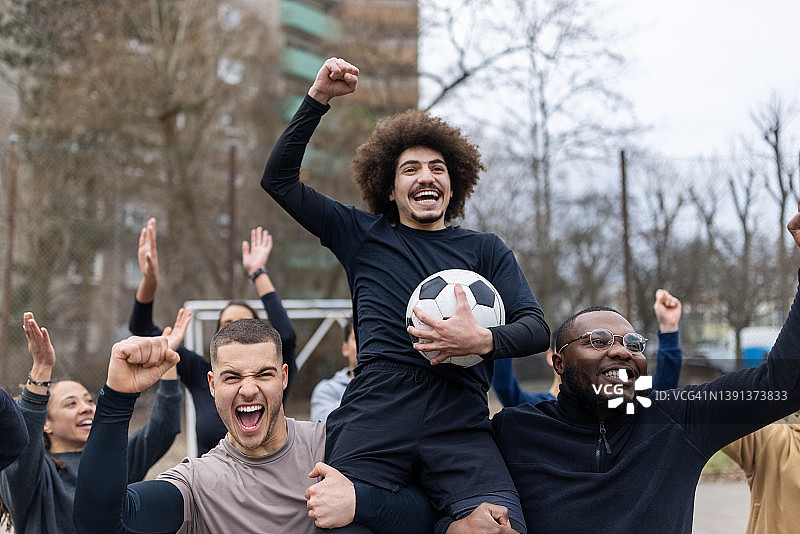 快乐的年轻男足球运动员在胜利中举起队友图片素材